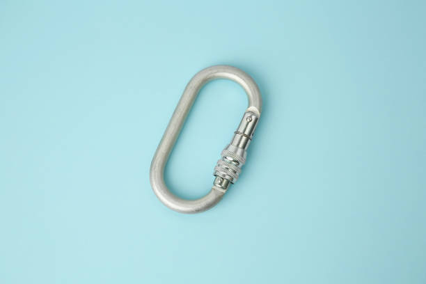 One metal carabiner on light blue background, above view