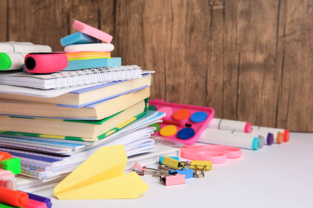 istock Many different books, paper plane and school stationery on white table, space for text. Back to school 1961061025