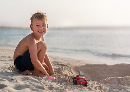 Little boy is playing with toys on the beach. Holidays in Dubai. Happy childhood concept