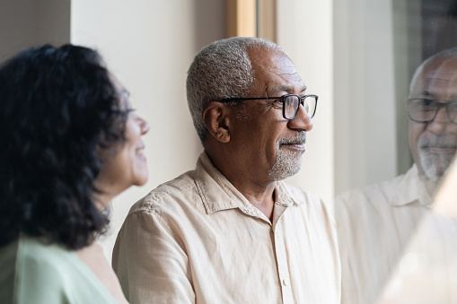 Close up of a senior couple looking out the window. Indoors.