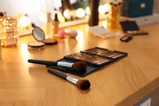 Brushes and other cosmetic products on wooden dressing table in makeup room