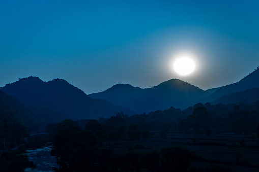 full moonrise dramatic landscape with mountain range at night from flat angle