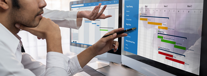 Project management team coordinating and update project planned schedule on computer using Gantt chart software in office. Business people planning time and deadline for company task. Trailblazing