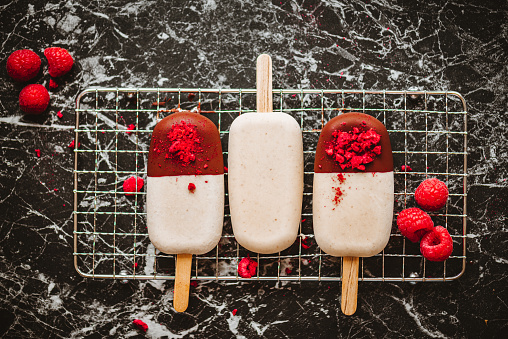 Vegan Vanilla Popsicles with chocolate coating and raspberries