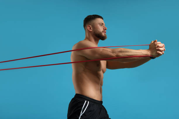 istock Muscular man exercising with elastic resistance band on light blue background 1961174094