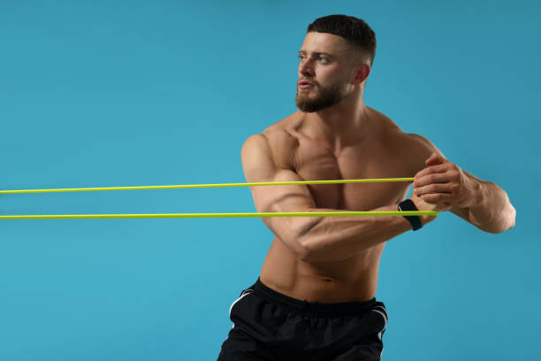 istock Muscular man exercising with elastic resistance band on light blue background 1961174099
