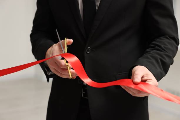istock Man cutting red ribbon with scissors on blurred background, closeup 1961176697