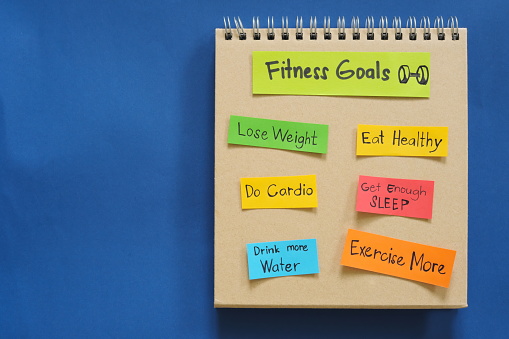 Fitness goals concept. Checklist of goals in note pad in blue background with copy space.