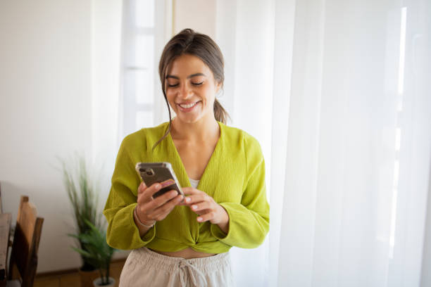 Happy young woman using phone Portrait of a young woman using smartphone happy using phone stock pictures, royalty-free photos & images