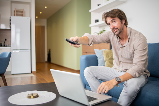 Young man watching TV at home and enjoying