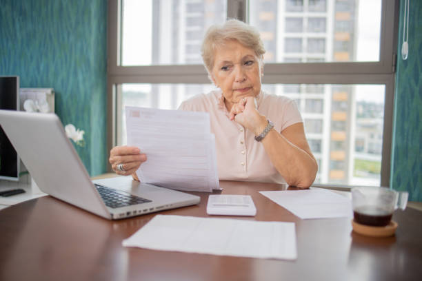 istock Senior woman using calculator while going through bills and home finances 1961209018