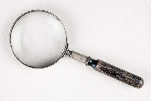 Antique vintage magnifying glass on paper background
