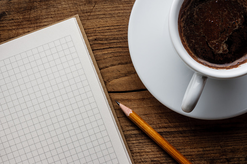 Notebook and cup coffee on wooden table