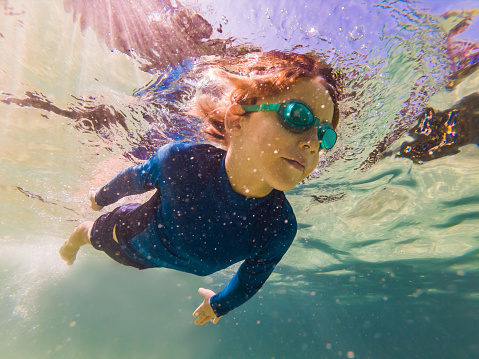 Underwater nature study, boy snorkeling in clear blue sea.