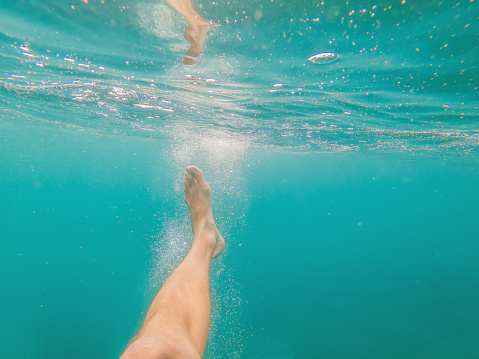 bare feet in the sea with clean water under sunlight. Sport, recreation or traveling concept.