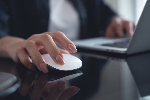 istock Female hand clicking computer mouse on office table. Business woman working on laptop computer and using wireless mouse, browsing the internet, searching the information, internet global networking concept 1961486483