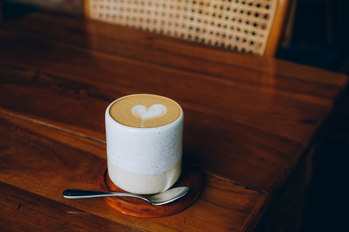 Stylish latte art in a ceramic mug on a wooden table, cozy ambiance.
