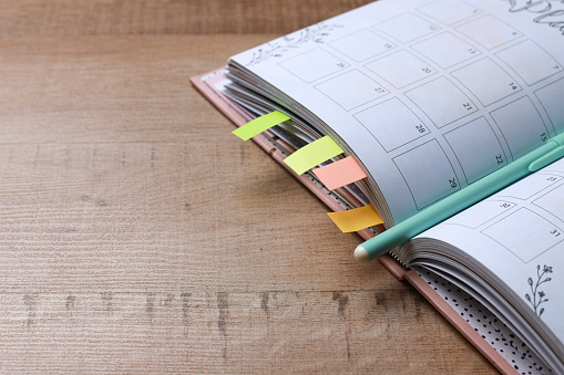 Colorful Page Markers on Diary Planner with Pen on Wooden Background