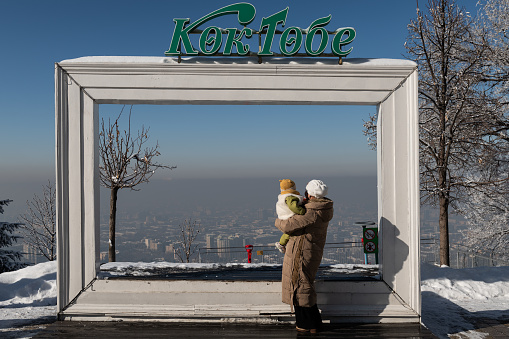Almaty, Kazakhstan. 01.22.2024. View of the smog-covered city of Almaty through a frame with the inscription 