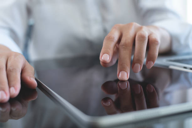 istock Businesswoman using digital tablet, finger touching on screen on office table, close up. Business woman surfing the internet, searching the information on digital tablet and working on laptop computer at office 1961550612