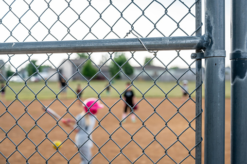 Parent view behind a chain link fence and home plate with a batter ready. High quality photo
