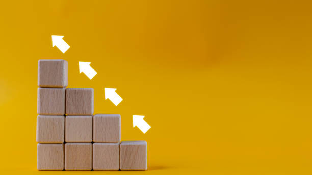 istock Rise arrow on wooden cube blocks, bar graph chart steps on yellows background, profit, benefit, income, business growth process, technology trend, economic improvement concepts. 1961627896