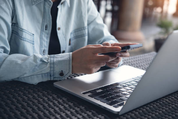 istock Casual business man using mobile smart phone and working on laptop computer on table at coffee shop 1961634135