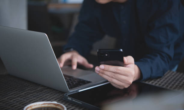 istock Young smart business man using mobile phone and working on laptop computer at office. Male freelancer online working, surfing the internet at coffee shop 1961635450