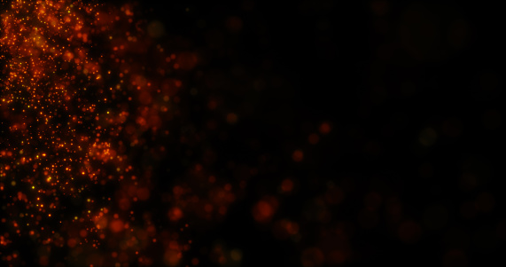 Blurred yellow orange abstract background of bokeh and small round particles of energy magical holiday flying dots on a black background.
