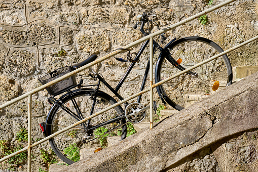 A black bicycle parked on the stairs of a home in an old town in Europe.