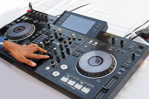 A boy operate turntable dJ mixer on a white table