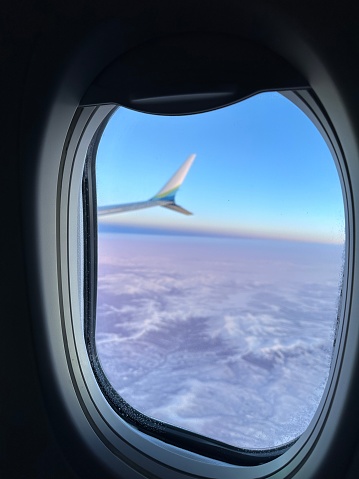 The window of the plane is often covered with frost, and the view from the window is full of blue sky, mountains and clouds