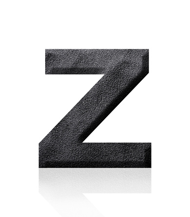Close-up of three-dimensional black sand alphabet letter Z on white background.