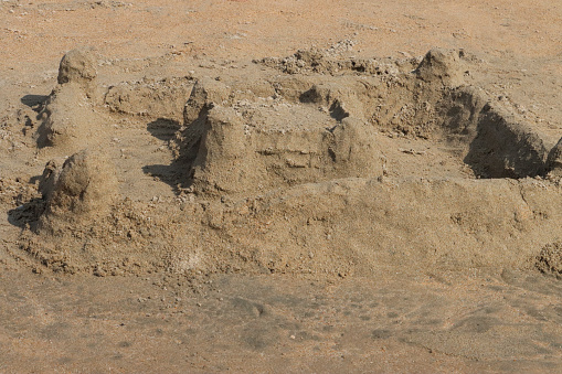 Stock photo showing close-up view of a complex sandcastle built on a sunny, golden sandy beach. Summer holiday, tourism and activities concept.