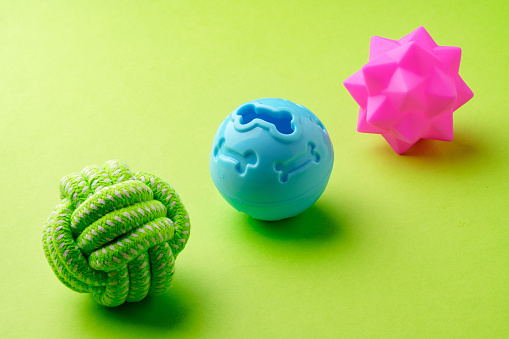 Colorful pet toys balls on green background close up