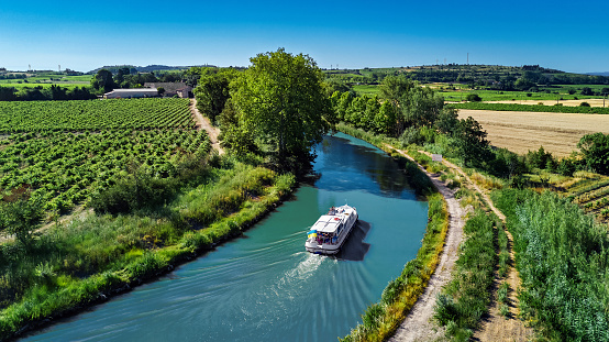 Aerial drone view of houseboat in Canal du Midi from above, family travel by boat, vacation in Southern France