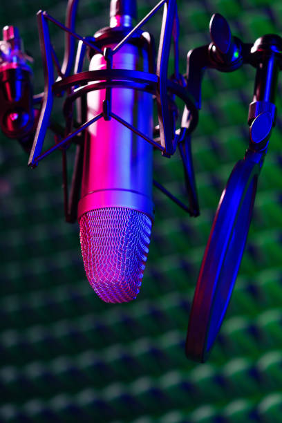 istock Professional studio microphone against acoustic foam panel background in neon light 1961813240