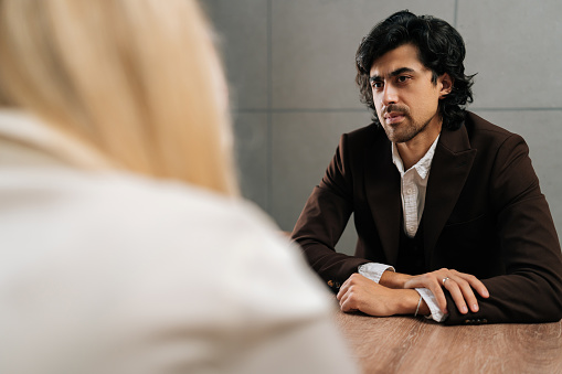 Back view of unrecognizable businesswoman having meeting with serious male colleague in office. Concept of company CEO negotiating with business partners, involved in dispute at briefing.