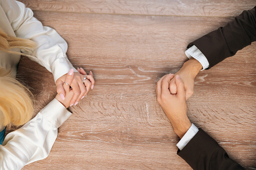 Closeup top view of clasped female and male hands negotiate at table. Concept confrontation, negotiators conflict, employees struggle for leadership at work, difficult job interview, hiring decision
