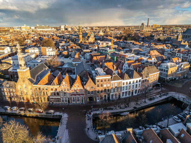 Early morning winter sun hitting the historical centre of Leiden, Rapenburg canal and his houses. Above a dramatic winter sky.
