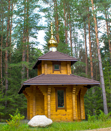 Church, temple, church in forest. Wooden temple on the background of pine trees. Large white stone