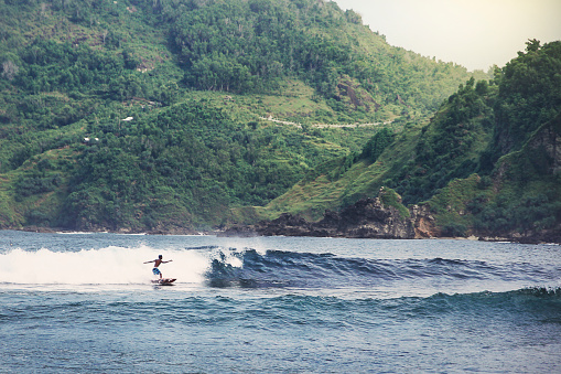 man surfing at wedi ombo beach, gunung kidul, yogyakarta