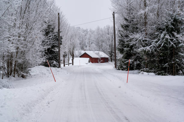 istock White snowy road with red farm building beside 1961854463