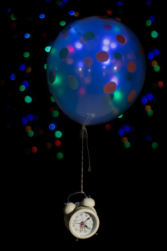Captured within this whimsical photograph is the essence of time suspended in a moment of playful transcendence. An ordinary alarm clock, delicately tethered to the whimsy of a vibrant balloon, transcends its utilitarian purpose, taking flight in a symbolic dance with passing time. The juxtaposition of the tethered clock against the buoyancy of the balloon evokes a sense of temporal liberation, inviting contemplation on the fleeting nature of moments. As the clock hovers weightlessly, it serves as a reminder that even amidst the ceaseless march of time, there exists a space for whimsy and the joyous abandonment of temporal constraints.