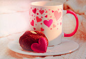 Cup of coffee and sweet chocolate ball cake, romance atmospheric mood, two red hearts, knitted warm plaid and sunlight. Breakfast for Valentines Day