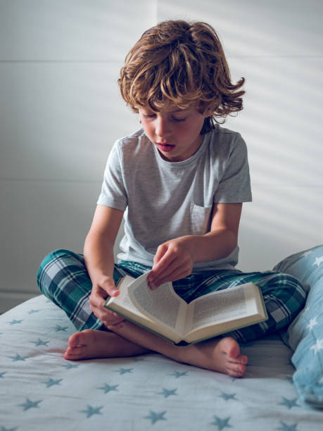 istock Little preschool boy sitting on bed and flipping through book 1961890922