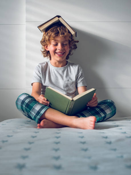 istock Cheerful preschool boy reading book on bed 1961893040