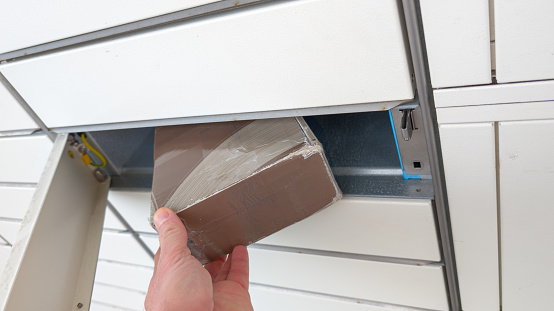 hand man puts carton package in the parcel locker pick up Empty label