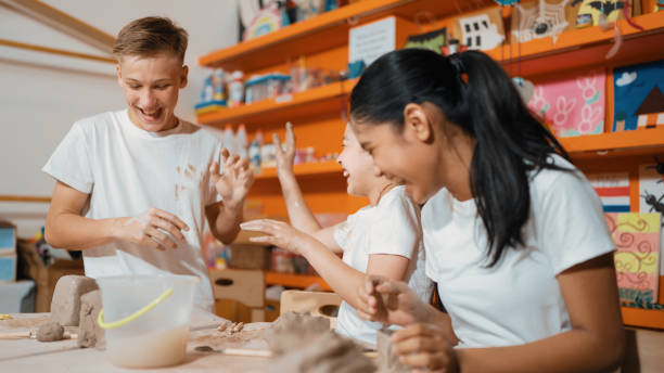 istock Student playing with friend while put the clay on shirt at class. Edification. 1961913668