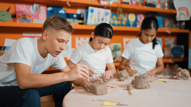 istock Teenager using carving tool working at clay at pottery workshop. Edification. 1961922648